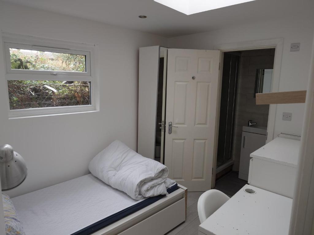 a small room with a bed and a window at The Old Guest House, 249A Norbury Avenue in Norbury