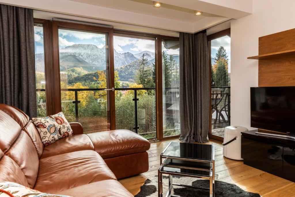 uma sala de estar com um sofá e uma grande janela em MOUNTAIN BASE Apartament Bellissimo em Zakopane