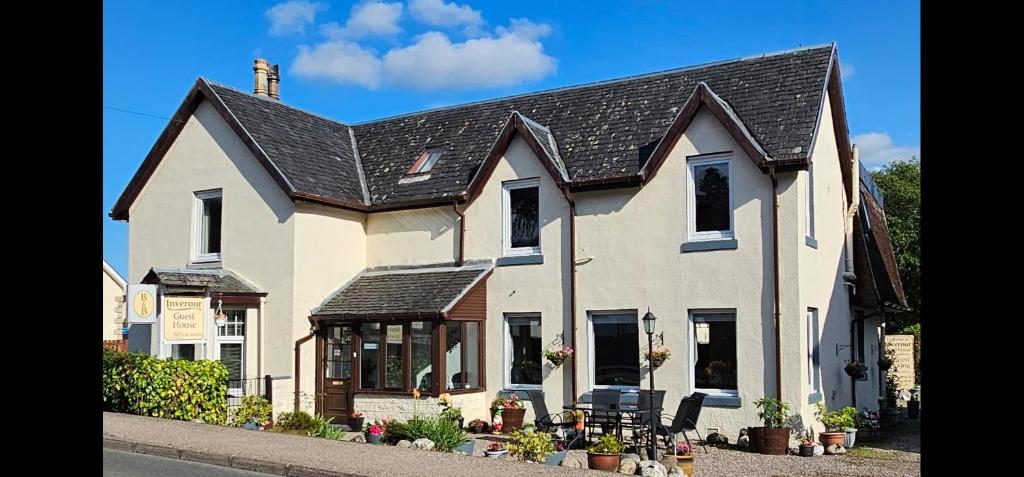 une grande maison blanche avec un toit noir dans l'établissement Inverour Guest House, à Spean Bridge