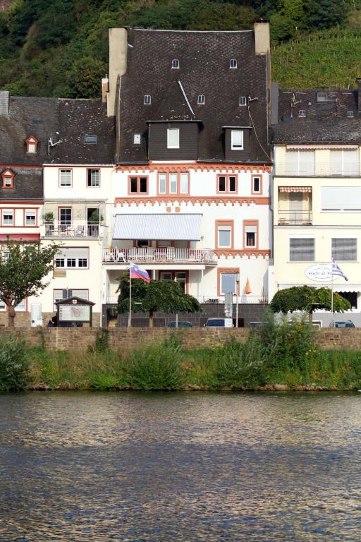 ein großes weißes Gebäude neben einem Wasserkörper in der Unterkunft Mosel View Old Town Apartments in Zell an der Mosel