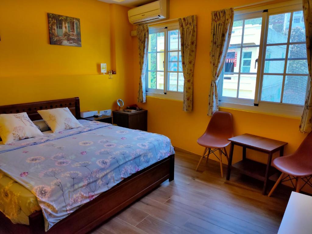 a bedroom with a bed with yellow walls and windows at ELLIE HOUSE in Xiaoliuqiu
