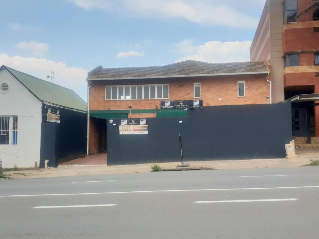 a building with a black fence next to a street at Camp Inn BnB in Pietermaritzburg