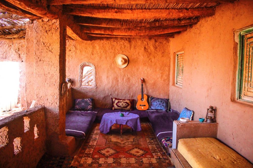 a living room with a couch and a guitar at Dar Nomad Tagounite in Zagora