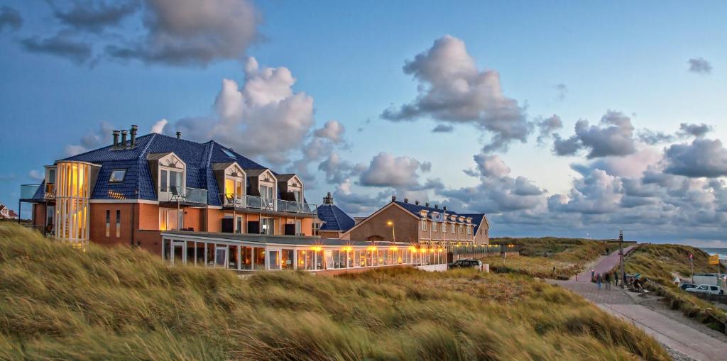 een groot huis bovenop een heuvel bij Strandhotel Noordzee in De Koog