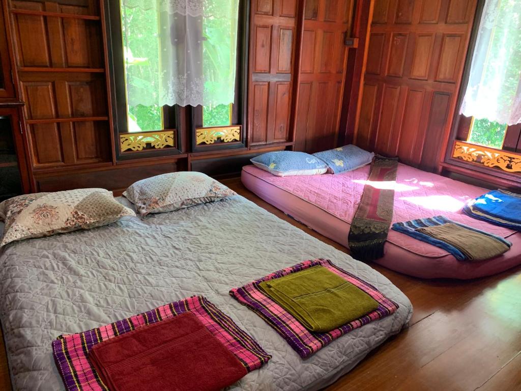 duas camas num quarto com duas janelas em โฮมสเตย์บ้านนายสิงโตเขาคูหา em Ban Khu Ha Nai (1)
