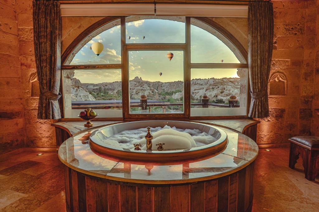 a room with a bath tub in front of a window at Şah Saray Cave Suites Halal Hotel in Göreme