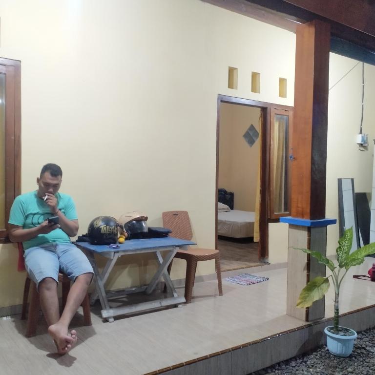 a man sitting at a table in a room at ijen Traveller homestay in Giri