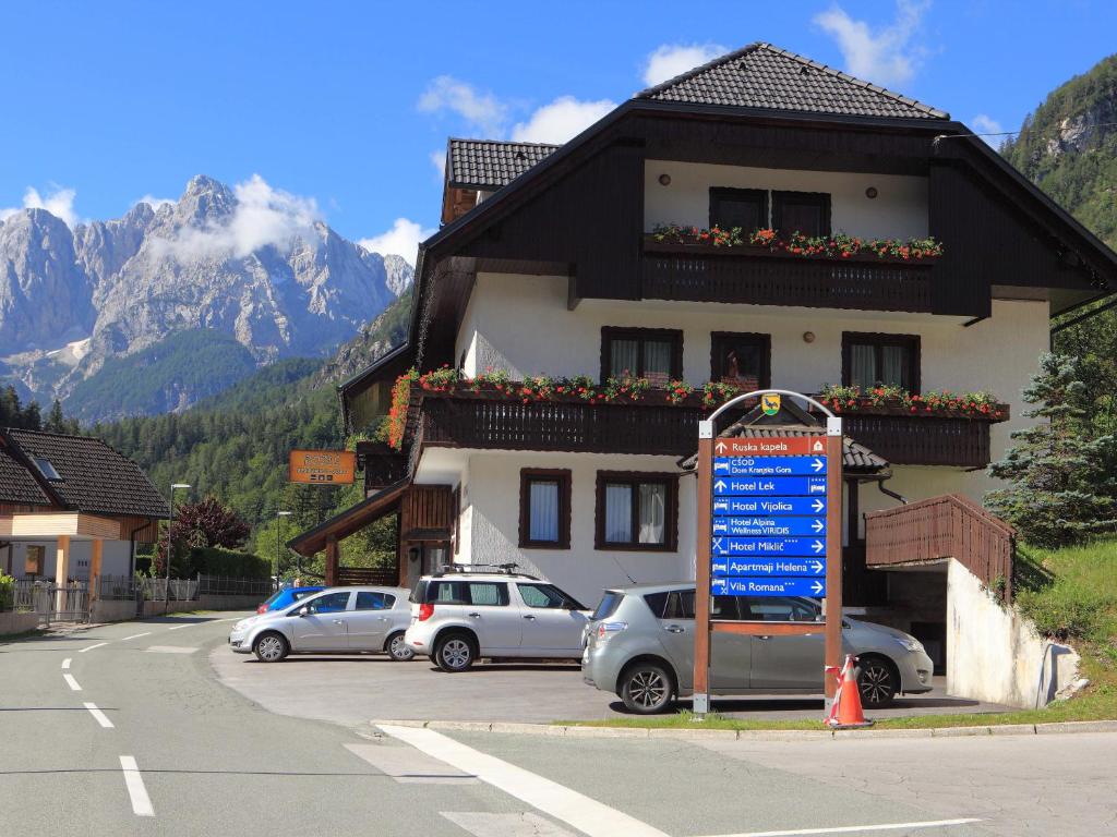 znak przed budynkiem z zaparkowanymi samochodami w obiekcie Apartments Rozle w mieście Kranjska Gora