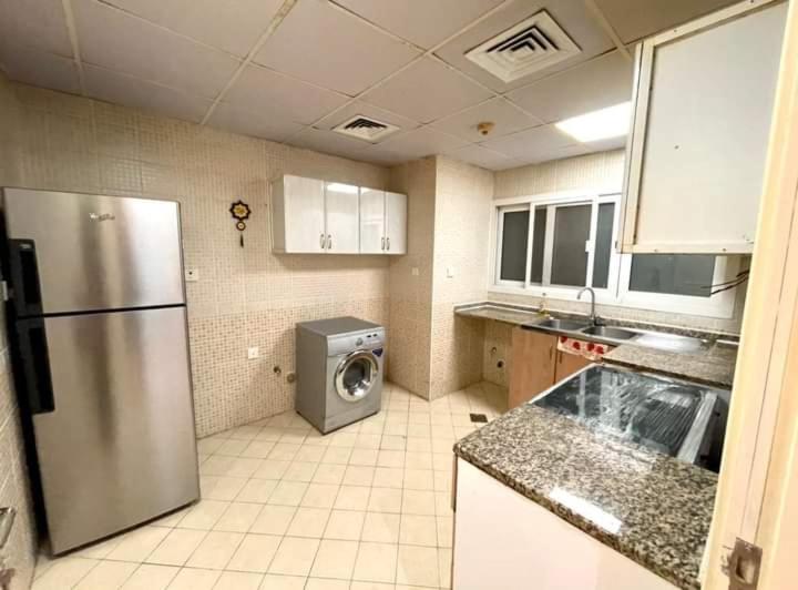 a kitchen with a refrigerator and a washing machine at شقه فندقيه in Dubai