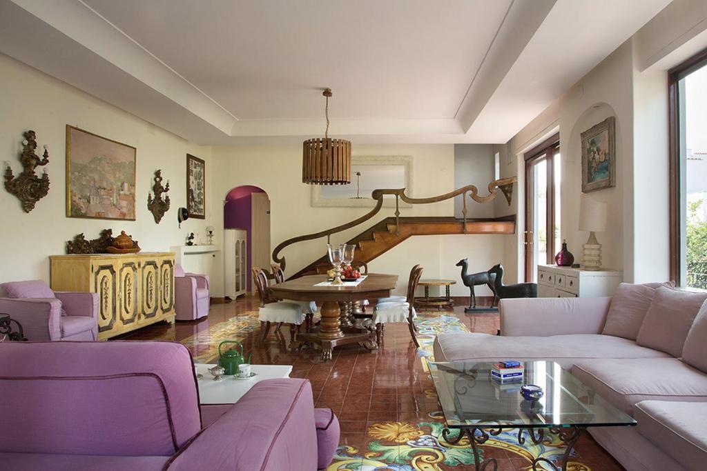 a living room with purple furniture and a table at Villa Gianturco - Luxury In The Green Island in Ischia