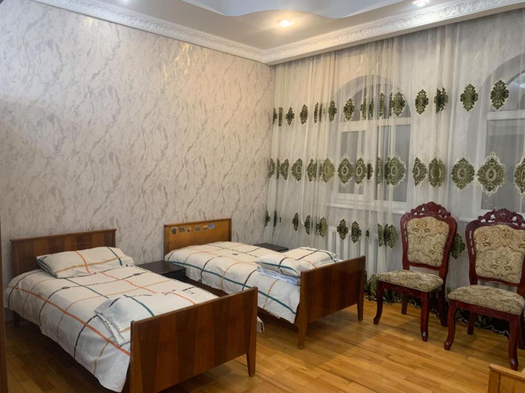 1 Schlafzimmer mit 2 Betten und 2 Stühlen in der Unterkunft Laola民宿 in Almaty