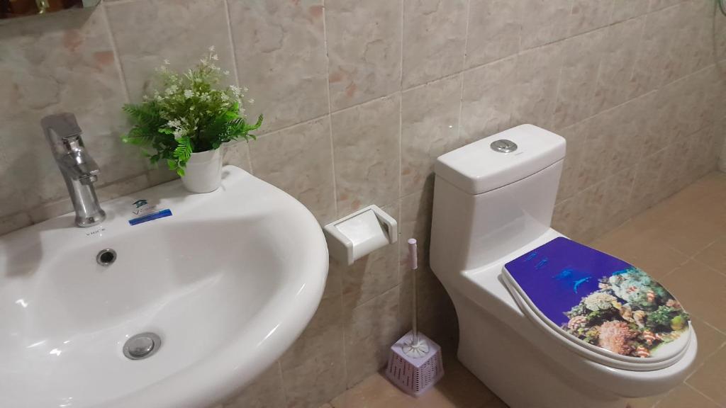 een badkamer met een wastafel en een toilet met een boek erop bij OLD Bonapriso Paisible Appart meublé 2 Chambres in Douala
