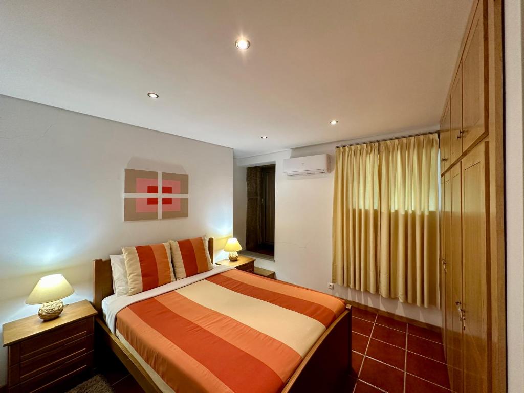 ein Schlafzimmer mit einem Bett, zwei Lampen und einem Fenster in der Unterkunft Casa da Clarinha in Penalva do Castelo