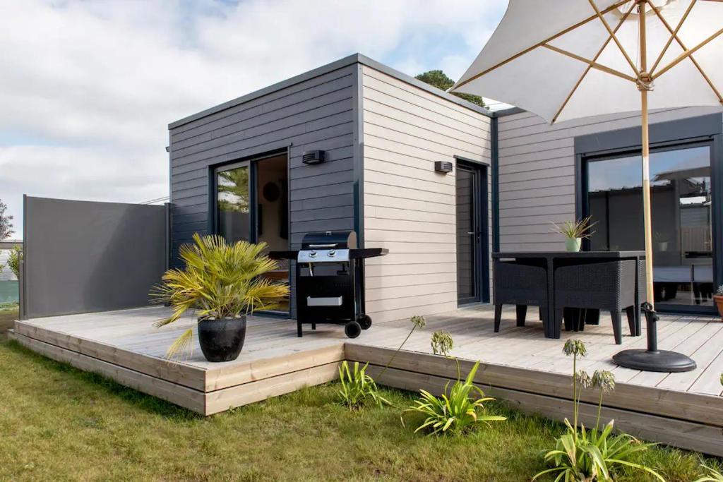 a small house with a table and an umbrella at Résidence Les Trois Mâts à Trestel, en bord de mer, sur la Côte de Granit Rose in Trévou-Tréguignec