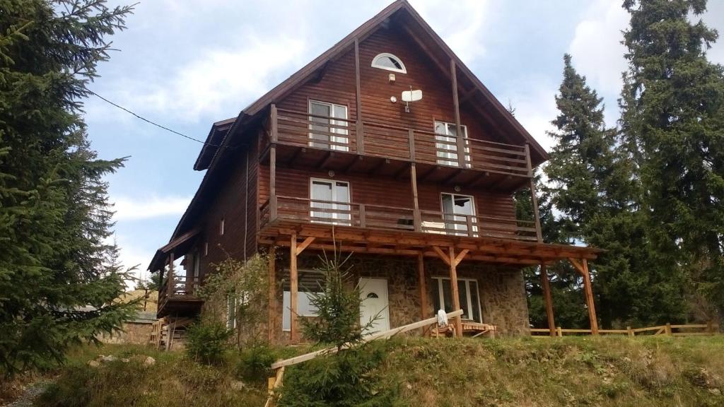 a large wooden house on top of a hill at Casa din Zori in Muntele Băişorii