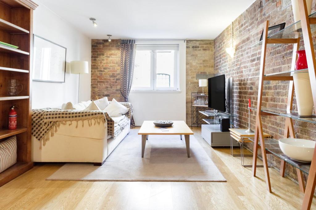 a living room with a couch and a tv at Designer Warehouse Two Bedrooms Converted, London Bridge in London