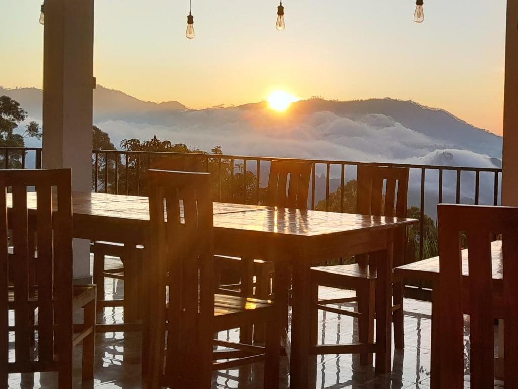 a table and chairs on a balcony with the sunset at Golden View Guest in Ella