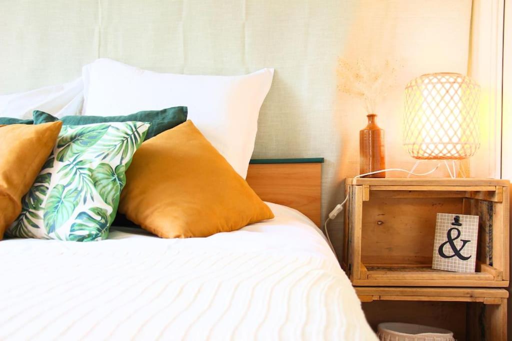 a bed with orange and green pillows and a night stand at Un cocon face à la mer in Plérin