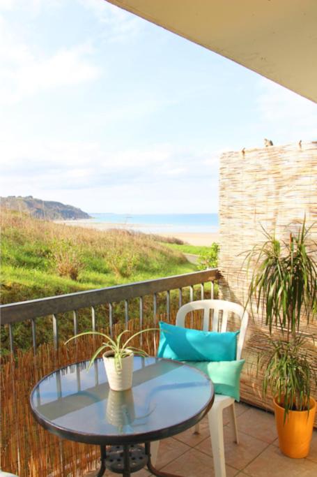 a table and chairs on a balcony with a view of the ocean at Un cocon face à la mer in Plérin