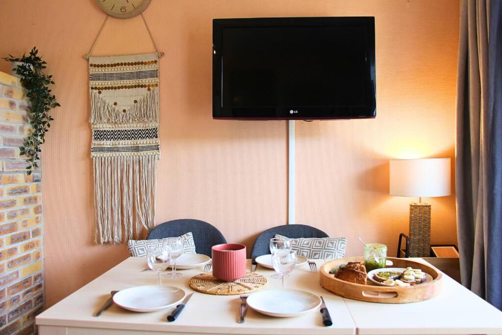 a table with plates of food and a television on a wall at Un cocon face à la mer in Plérin