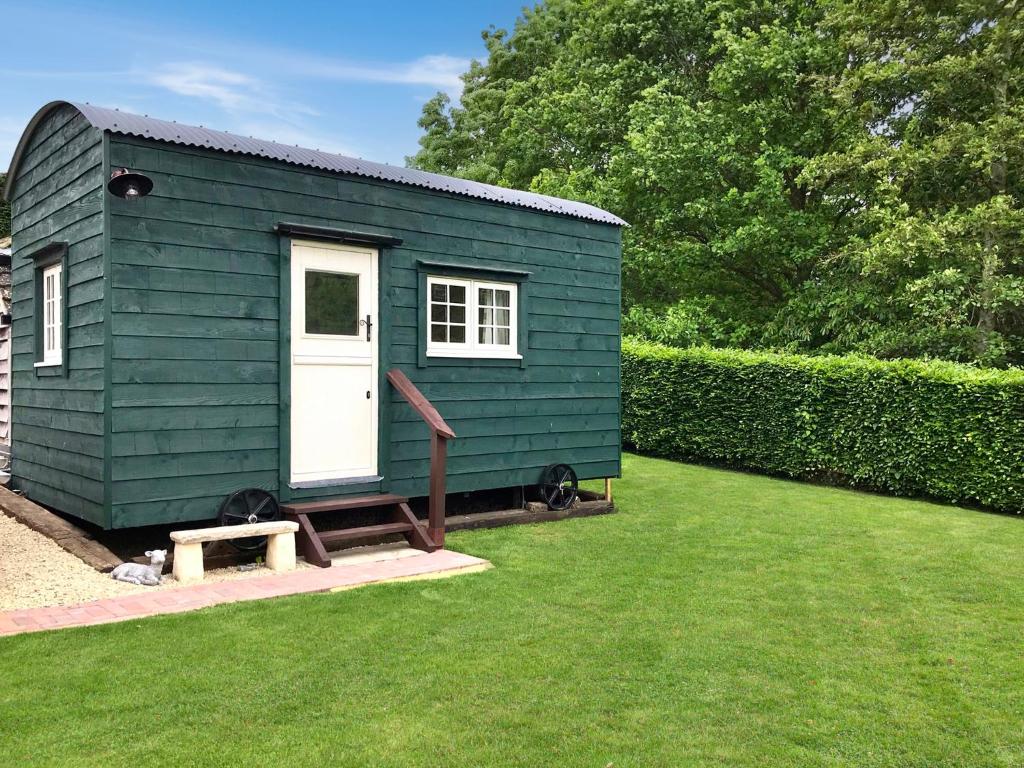 a green tiny house sitting in a yard at Beautiful Shepherd's Hut - Lois Weedon in Weston