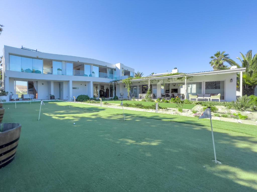 a large house with a putting green in front of it at Peach on Beach Boutique Guesthouse in Bloubergstrand