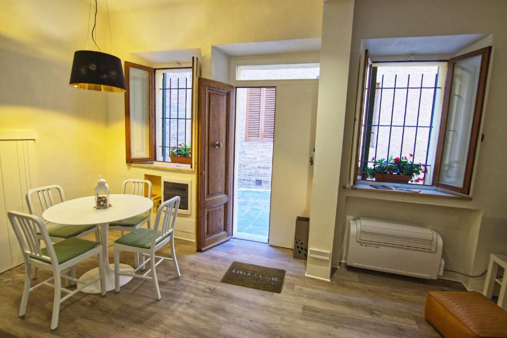 uma sala de jantar com mesa, cadeiras e janelas em Magione 10 em Siena