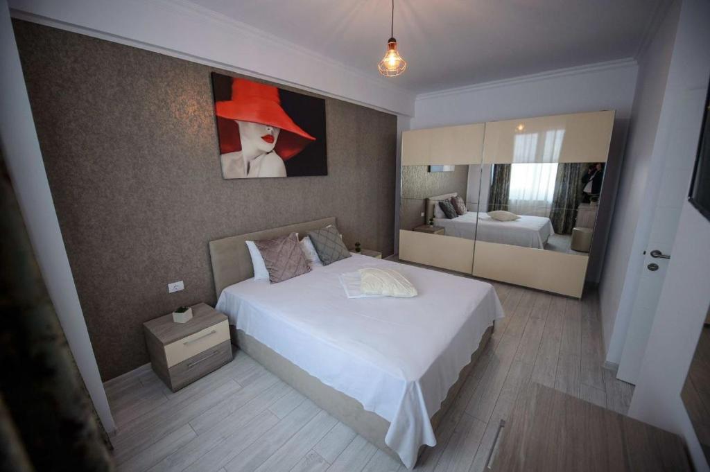 Un dormitorio con una cama blanca y una pintura en la pared en ELEGANCE APARTMENT, en Marina di Monasterace