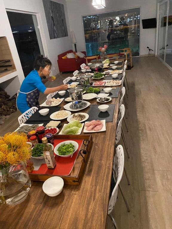 a woman is preparing a long table of food at Peach on Beach Boutique Guesthouse in Bloubergstrand