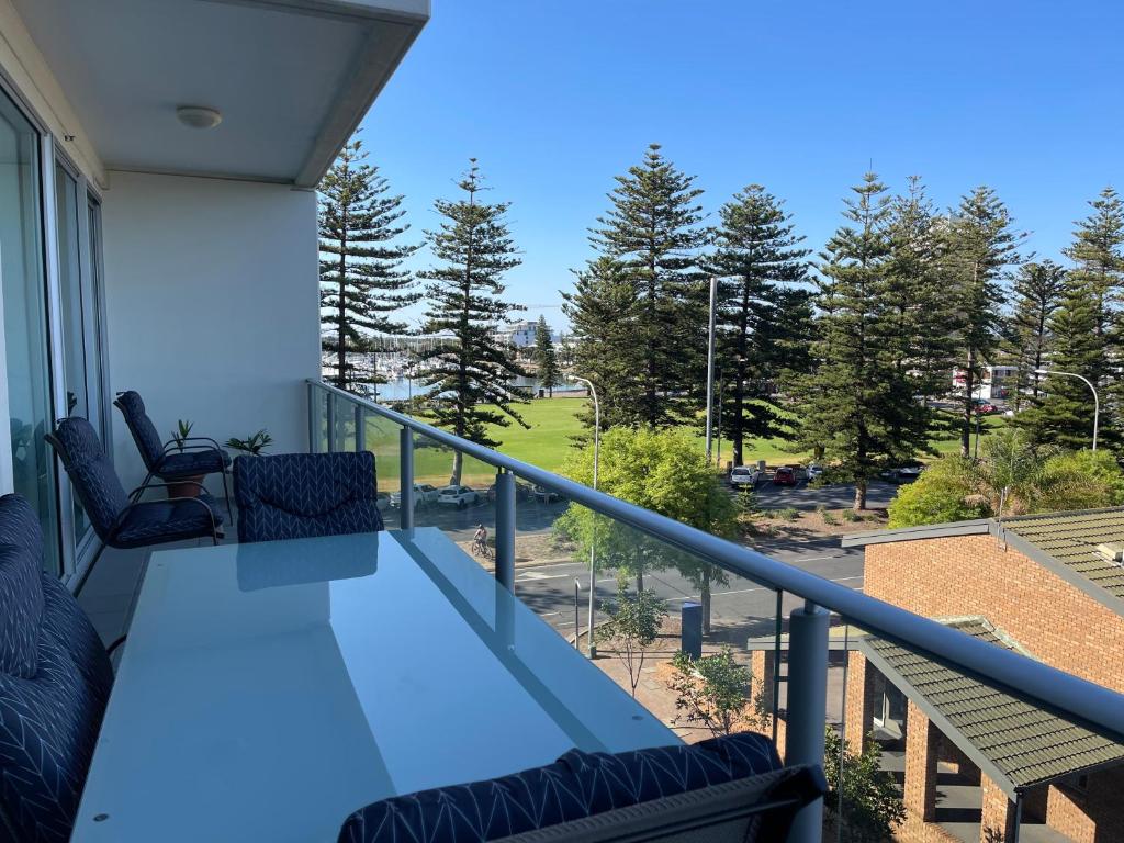 a balcony with a table and chairs and a view of a park at Glenelg resort style beachside apartment in Glenelg