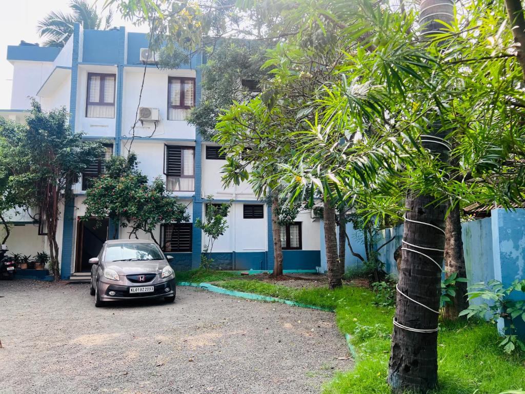 un coche aparcado frente a un edificio azul y blanco en Hotel Sunday - Townhouse Club Airport Trivandrum, en Trivandrum