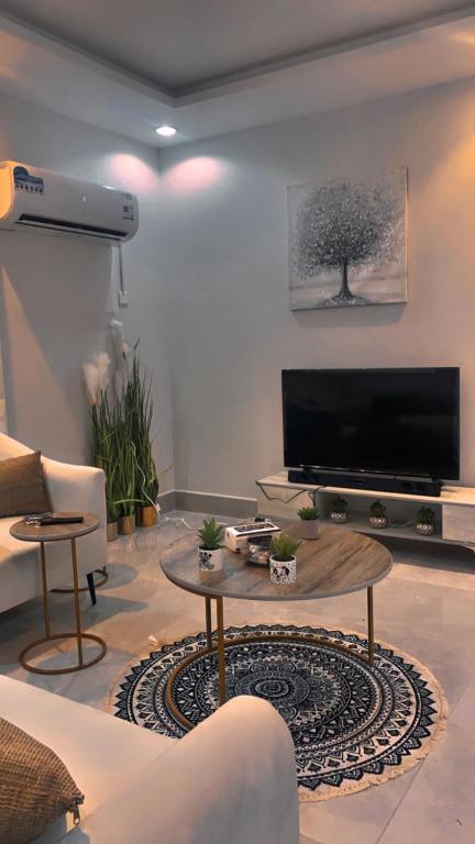 ein Wohnzimmer mit einem TV und einem Couchtisch in der Unterkunft شقة الغدير in Riad