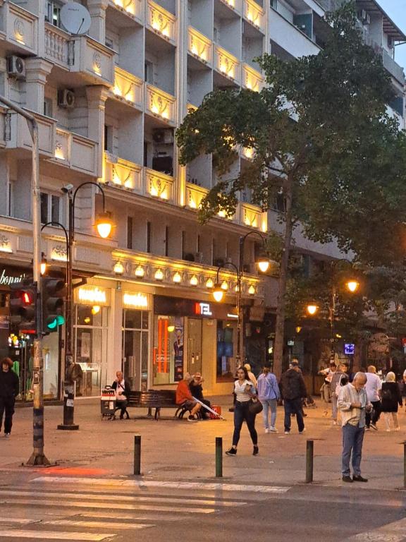 a group of people walking on a city street at night at Alpi Hostel in Skopje