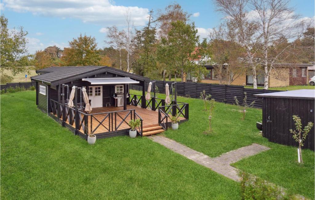 a black house with a playground in the grass at Cozy Home In Helsinge With Kitchen in Helsinge