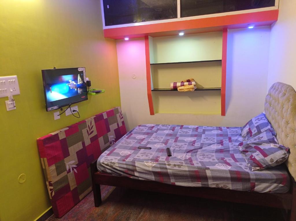 a bedroom with a bed and a tv on a wall at Siddharth illam in Puducherry