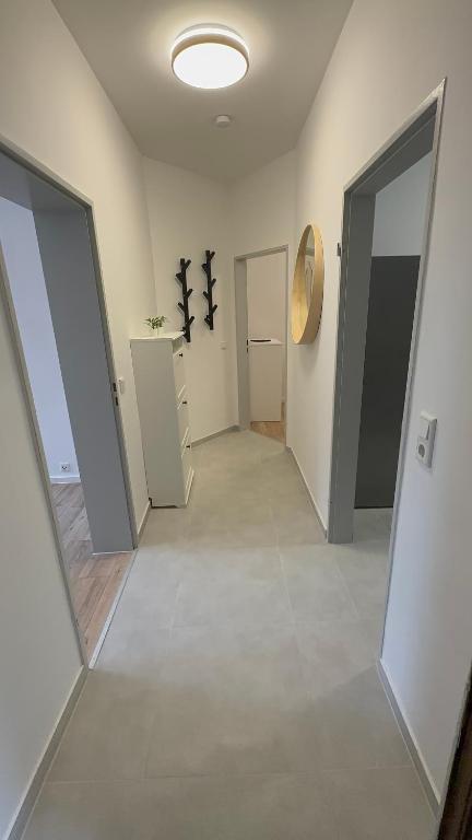 un couloir vide avec deux portes et une pièce avec un miroir dans l'établissement One100 I Appartment am Schaufenster Fischereihafen, à Bremerhaven