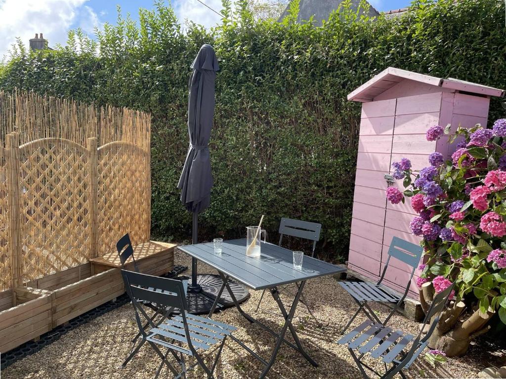- une table, des chaises et un parasol dans le jardin dans l'établissement Maison 5 pers à 640m de la plage de Trestraou à PERROS-GUIREC - Réf 909, à Perros-Guirec