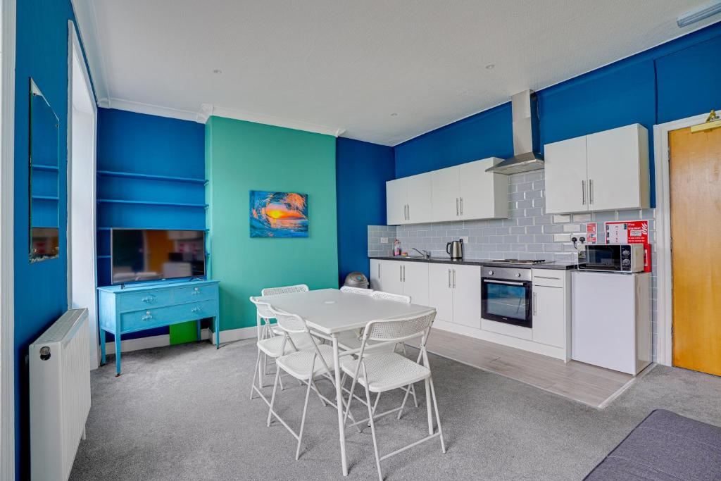 cocina con paredes azules, mesa y sillas en One-Bedroom Apartment: Sleeps 4 Comfortably, en Berwick-Upon-Tweed