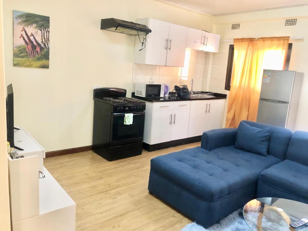 a living room with a blue couch and a kitchen at LouieVille One Bedroom Apartment in Lusaka