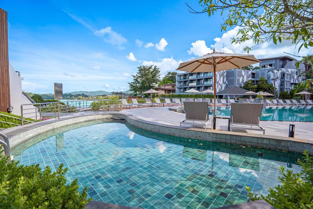 a swimming pool with two chairs and an umbrella at Orchidacea Resort - Kata Beach in Kata Beach