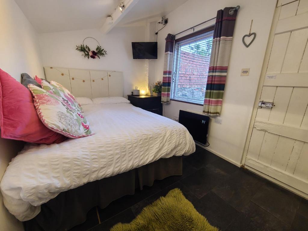 a bedroom with a white bed with pillows and a window at THE OLD WASH HOUSE, Prestatyn, North Wales - an original Victorian laundry now a unique little dog-friendly let, a 5 min walk to beach & town! in Prestatyn