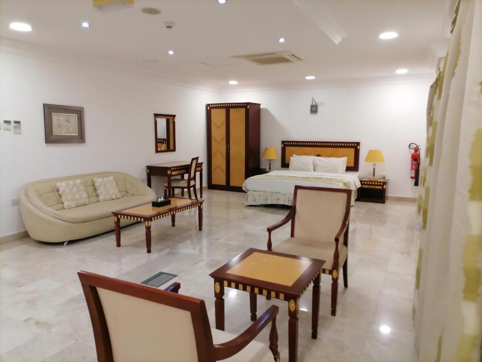 a hotel room with a bed and a couch and chairs at Pioneer Hotel Apartments Muscat in Muscat