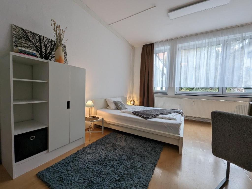 a white bedroom with a bed and a large window at Pension am Park in Pforzheim