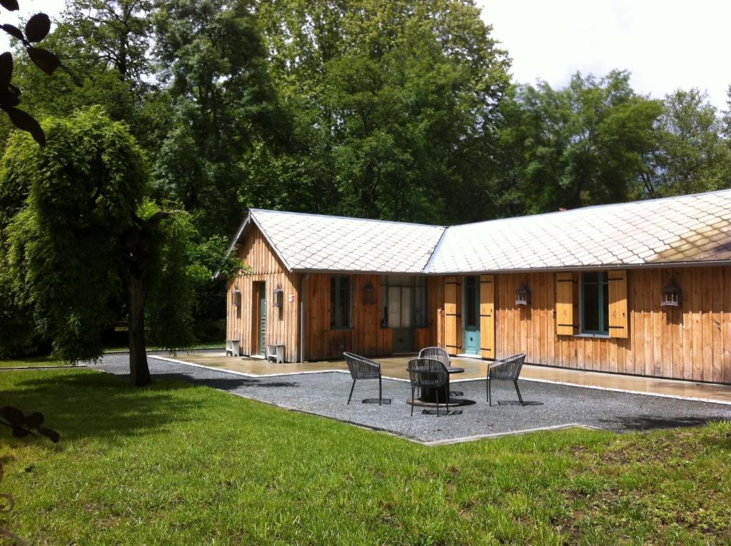 ein Holzhaus mit einem Tisch und Stühlen davor in der Unterkunft Le Pavillon du Lac in La Brede