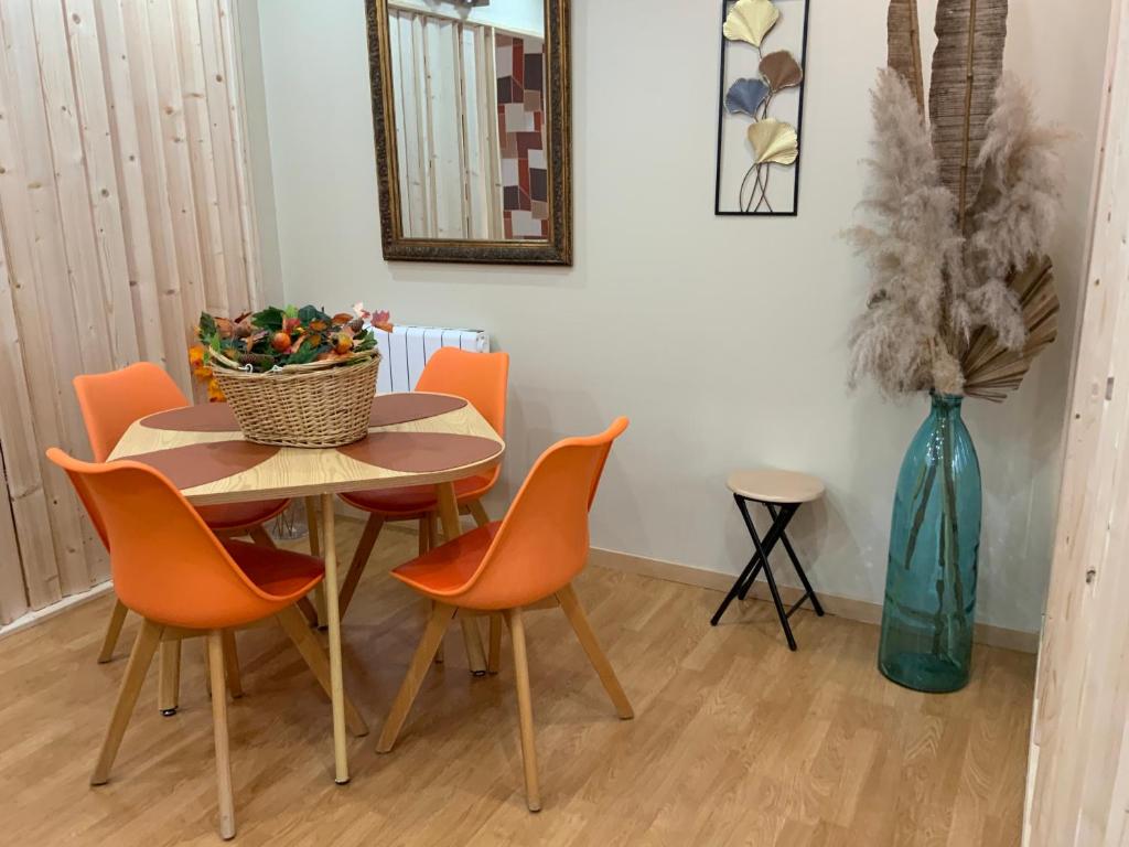 a dining room table with orange chairs and a vase at Family lodg in Calais