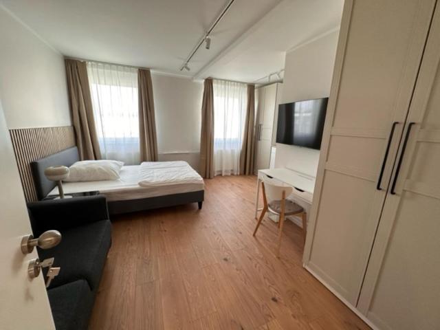 a bedroom with a bed and a desk and a television at ELBI Apartment in Frankfurt/Main