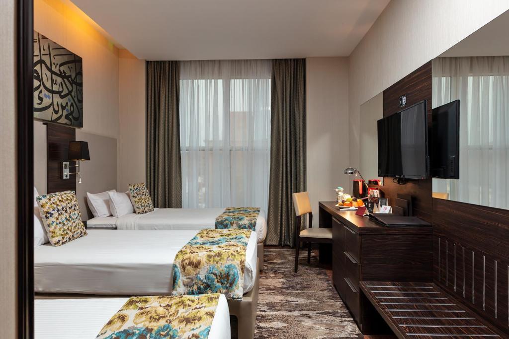 a hotel room with two beds and a television at M Hotel Makkah by Millennium in Makkah