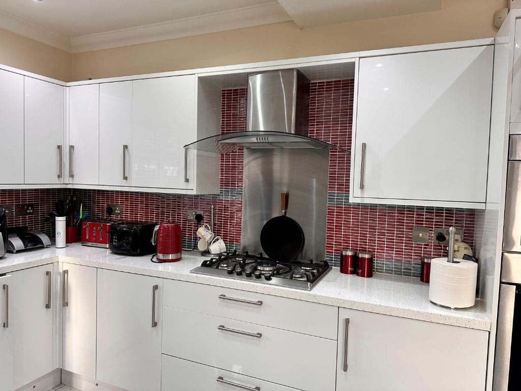 a kitchen with white cabinets and a stove top oven at Hestia Travel Slough in Slough