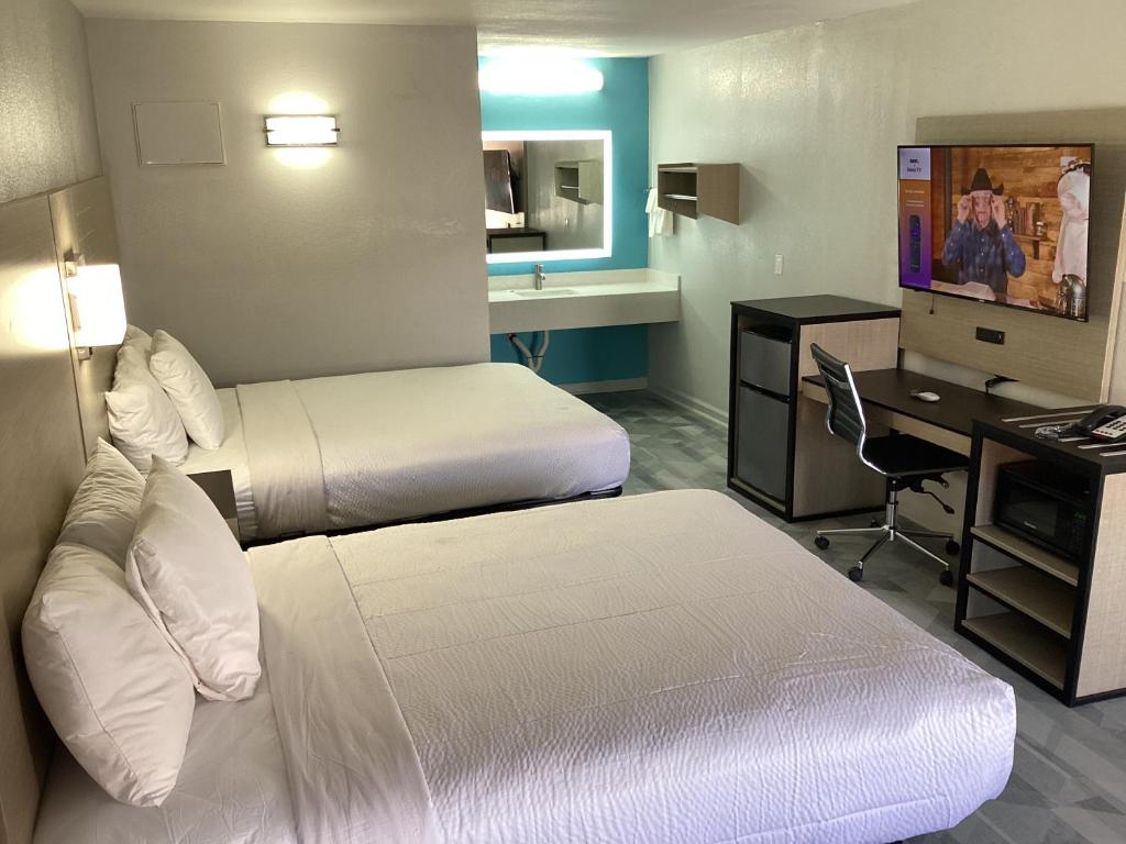 a hotel room with two beds and a desk at Pleasanton Executive Inn in Pleasanton