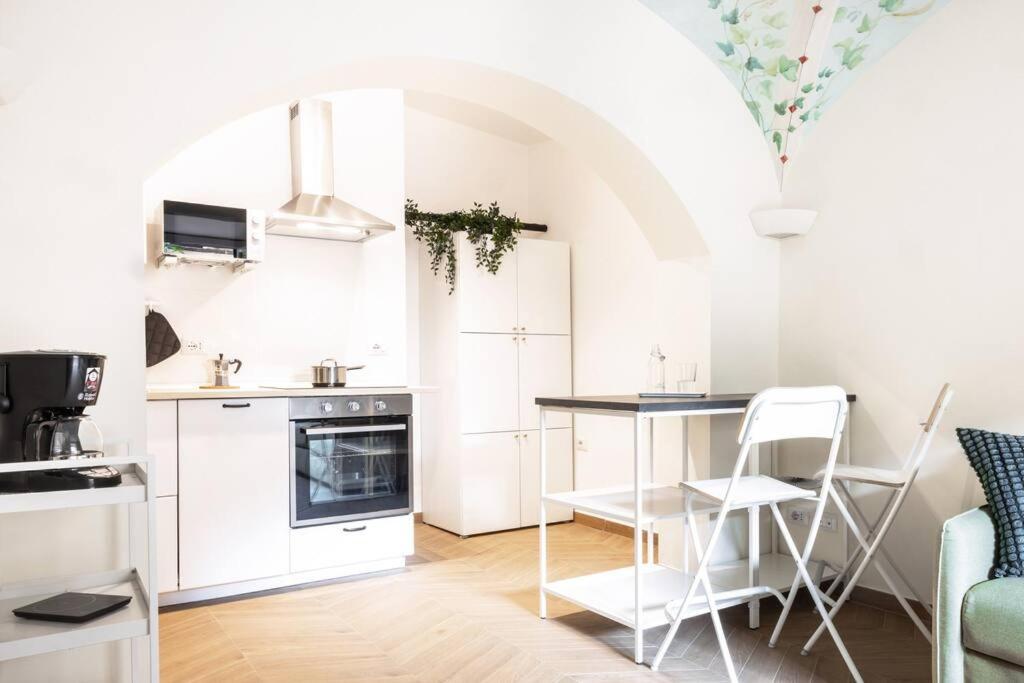 - une cuisine avec des placards blancs, une table et des chaises dans l'établissement Casa Redi, à Rome